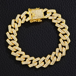 Close-up of golden Cuban link bracelet with white pavé rhinestones on black leather