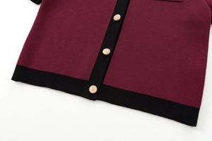 Detail of burgundy knit top showing gold lion crest buttons and black contrast trim