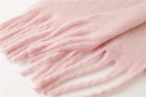Vue détaillée de la texture d'une écharpe rose en mohair avec de doux pompons frangés