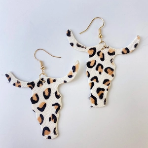 Détail de boucles d'oreilles crâne de vache en fausse fourrure léopard et crochets dorés