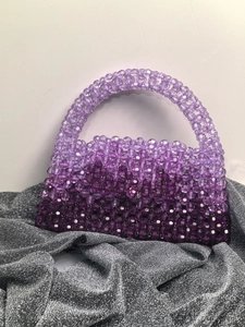 Detail of handmade purple gradient beaded handbag with translucent woven texture