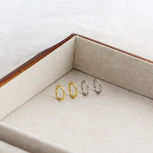 Detailed shot of gold and silver hammered hoop earrings displayed in a linen lined box