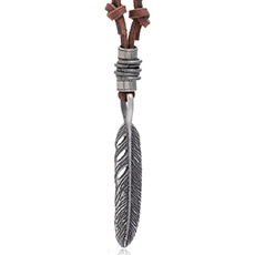 Close-up of vintage silver feather pendant with brown leather cord and metal ring detailing