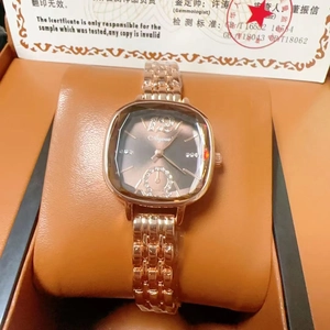 Detailed close-up of rose gold barrel-shaped watch with crystal scales on an orange pillow