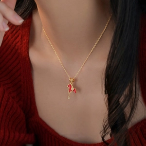 Macro view of 18K gold plated horse pendant with red enamel and zircon on a gold necklace