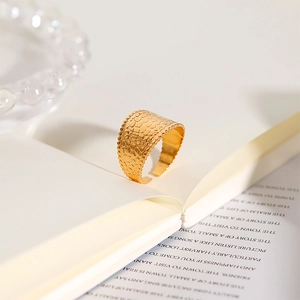 Detailed macro view of gold-plated stainless steel ring with crocodile texture in a book