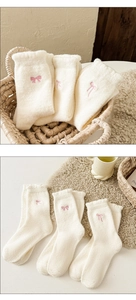 Detail view of 3 pairs of thick plush white socks with cute pink embroidered bows