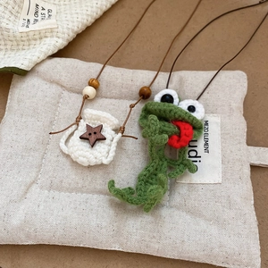 Close-up of hand-crocheted green frog and white bag pendant with wooden star button