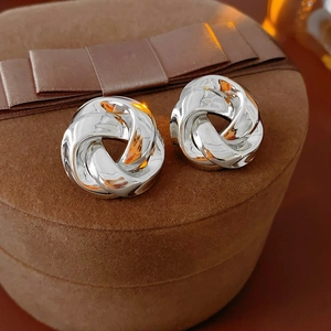 Gros plan de boucles d'oreilles nœud argentées sur un écrin en velours marron chic