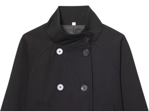 Detail of the high stand collar and double-breasted buttons on a black wool coat