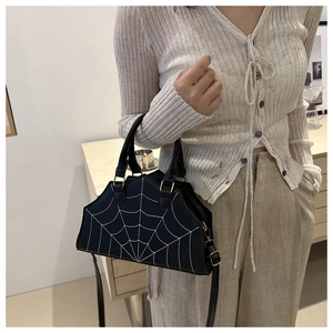 Detail shot of black PU leather handbag featuring unique white spider web embroidery pattern