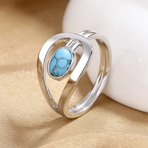 Close-up of a silver criss-cross ring featuring a blue turquoise stone on a gold fabric
