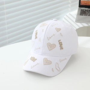 Détail d'une casquette blanche en coton avec broderie dorée love et motif de cœur mignon