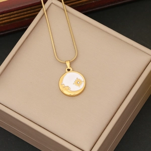 Collana dorata con stella e luna e ciondolo a girasole su scatola portagioie in pelle beige