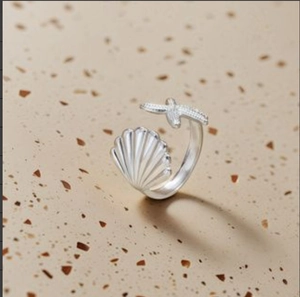 Macro detail of silver-tone open ring featuring a seashell and starfish design