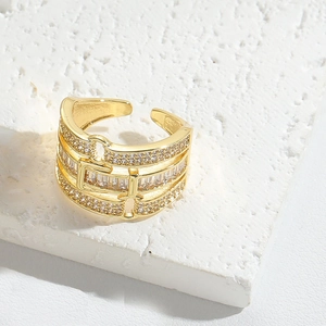 Detailed close-up of golden wide band ring with square zircon and horsebit design
