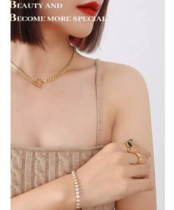 Detalle del collar con hebilla OT dorada y pulsera de tenis de circonitas brillantes