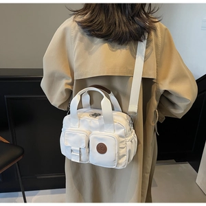 Detailansicht einer weißen Nylon-Umhängetasche mit Doppelgriffen und Multi-Taschen-Design