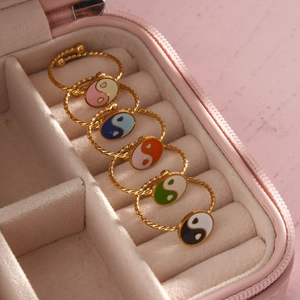 Detail of colorful enamel Yin Yang rings with gold twisted bands in a pink jewelry box
