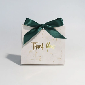 Detail of marble pattern gift bag with gold foil Thank You text and dark green ribbon bow