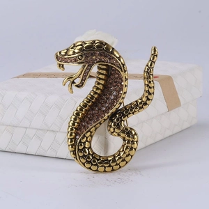 Macro view of vintage cobra snake brooch with brown crystals on a textured gift box