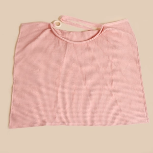 Detail of pink cotton waffle weave nursing cover with adjustable neck ring and strap