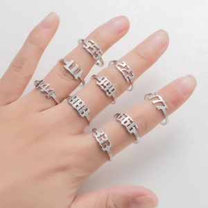 Detail view of nine stainless steel angel number rings from 111 to 999 worn on fingers