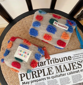 Dettaglio ravvicinato della borsa trucco in feltro fatta a mano con pompon colorati