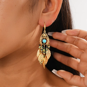 Détail de boucles d'oreilles vintage en or avec perles bleues et pendentifs plumes