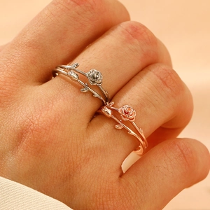 Close-up of intertwined rose rings in silver and rose gold finishes on fingers
