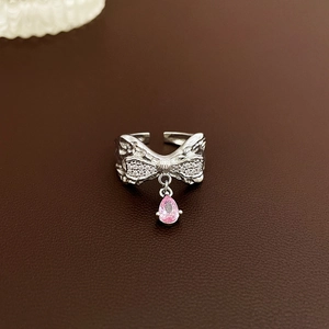 Detailed macro view of silver bow ring featuring a dangling pink teardrop zircon stone