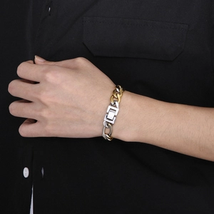 Detail of silver and gold toned stainless steel Figaro link chain bracelet for men