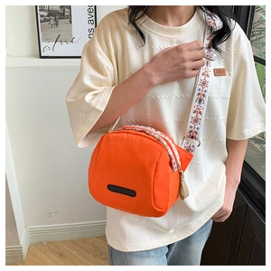 Close-up of orange waterproof nylon crossbody bag with ethnic pattern wide strap