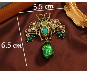 Detail view of vintage beetle brooch with emerald stones and pearls on satin background