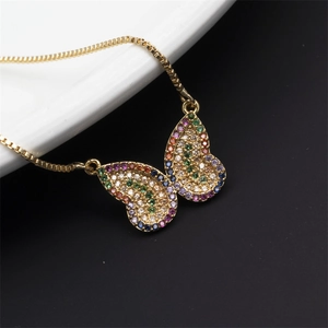 Detail of a golden butterfly necklace featuring colorful inlaid crystals on a split background