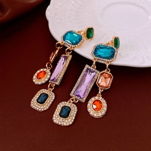 Detail of vintage gold earrings featuring multi-color stones and crystal tassels