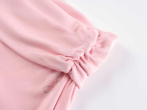 Detailed view of pink modal fabric with silver rhinestone letters and delicate lace trim