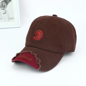 Close-up of embroidered letter D on brown cotton baseball cap with red distressed brim