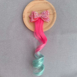 Detail of pink sequin bow hair clip with long pink to blue gradient curly hair extension