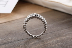 Macro detail of silver croissant twist ring with spiral textured design on dark wood