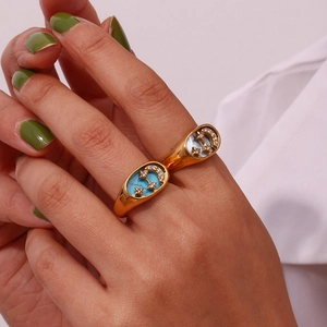 Detailed close-up of 18K gold double ring with turquoise and pearl moon-star charms