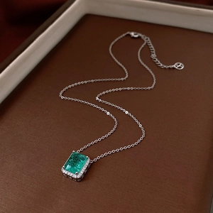Detail view of silver necklace with square green gemstone pendant and zircon accents