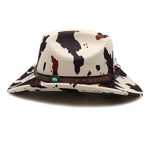 Detail of cow print cowboy hat featuring a leather band with turquoise stone and studs