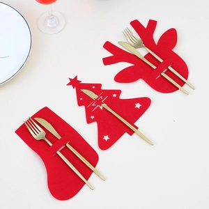 Detail of red felt Christmas cutlery holders in sock, tree, and elk shapes with gold silverware