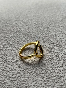 Close-up of golden twist knot ring on textured stone background for a minimalist style