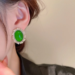 Close-up of vintage oval green gemstone stud earring with sparkling zircon details