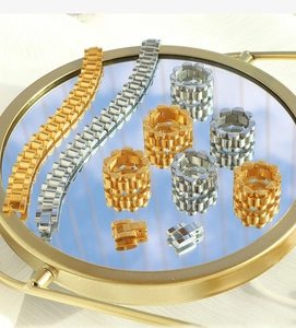Detailed set of gold and silver watchband style chain bracelets and rings on a mirror tray