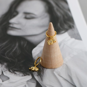 Detail of gold-plated elephant drop earrings with white zircon stones on a wooden stand