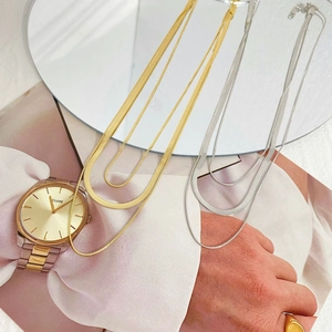 Elegant gold and silver double layered snake chain necklaces styled on a magazine background
