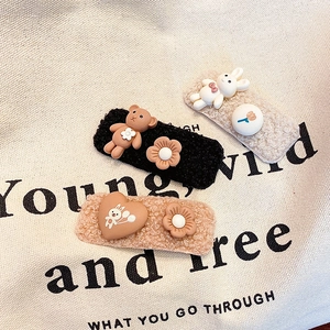 Three plush hair clips with cartoon bear and rabbit charms on a canvas background